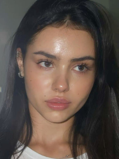 Close-up of a person with long dark hair wearing a white shirt.