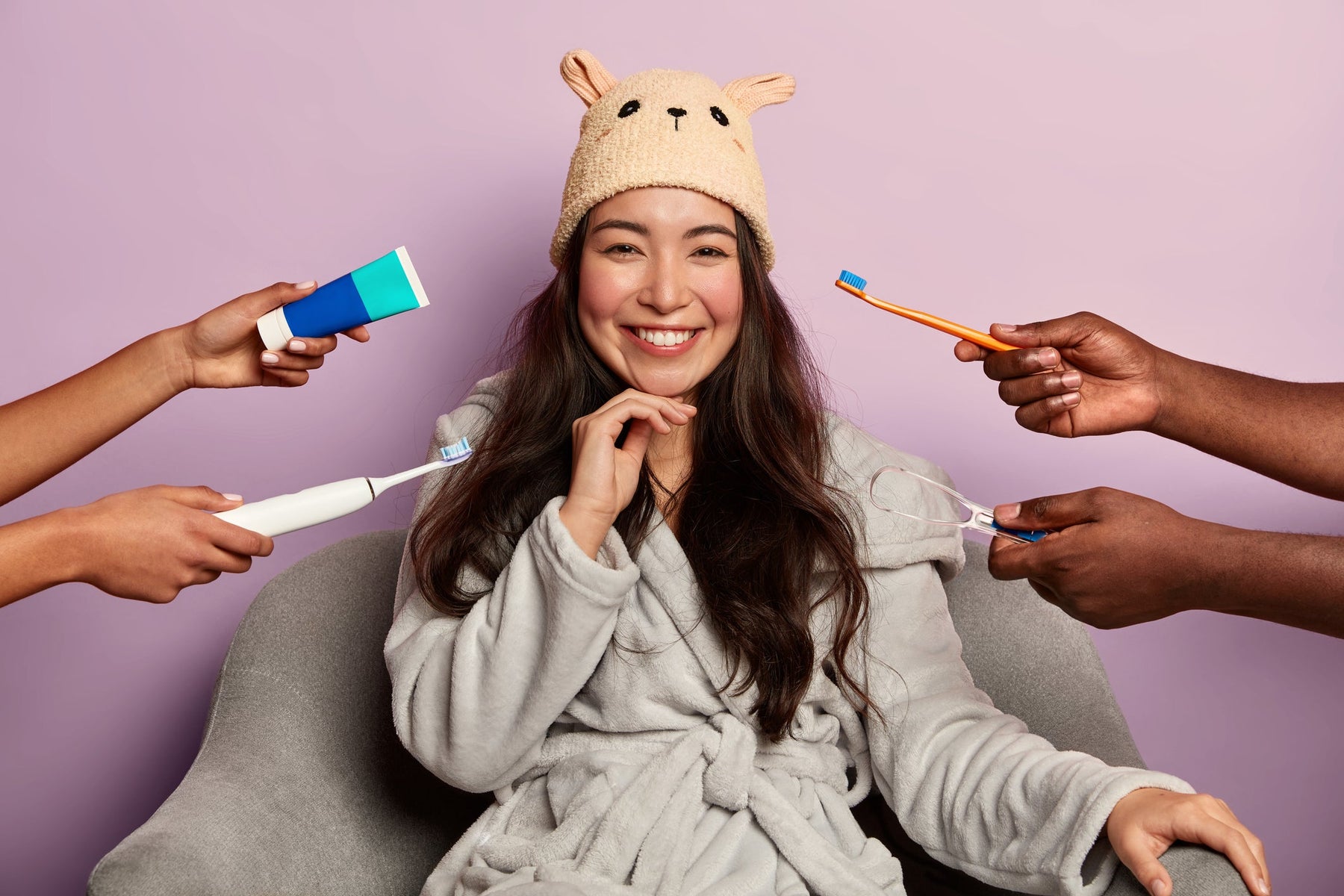 Woman in a robe surrounded by hands holding dental hygiene products against a purple background